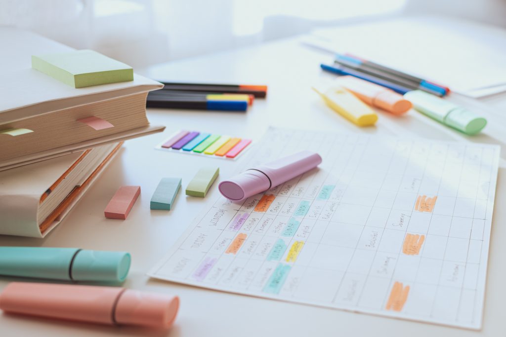 Auf einem Tisch liegen bunte Textmarker und bunte Zettel verteilt.